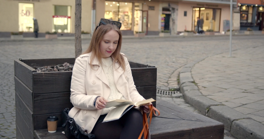 Girl reading while sitting on bench in old city | Shutterstock HD Video #1091821137
