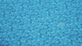 closeup of the bottom drain of a swimming pool with the water moving through the air and changing the shape of the decoration of the squares inside
