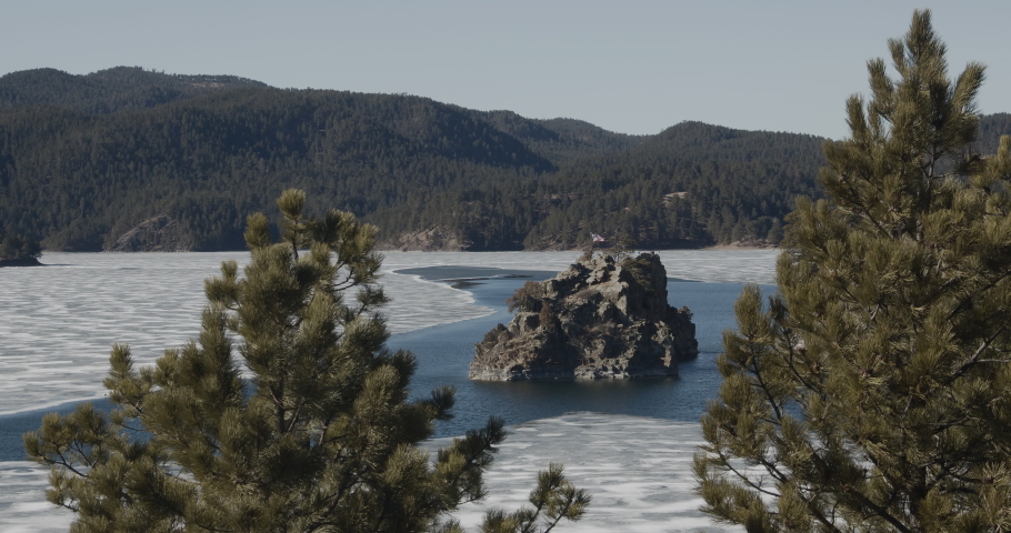 Black Hills South Dakota United States of America - 02 19 2022: Lake Pactola, the largest reservoir in the Black Hills with the United States flag flying in the background.