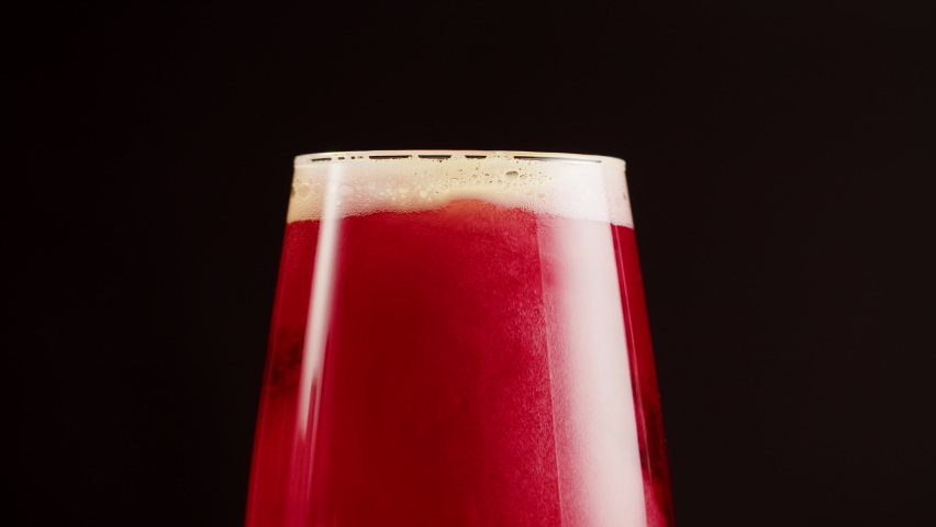 Foamy cherry beer in glass close-up, belgian lambic. Alcohol red fruit drink, cider on black background.  Royalty-Free Stock Footage #1091824467