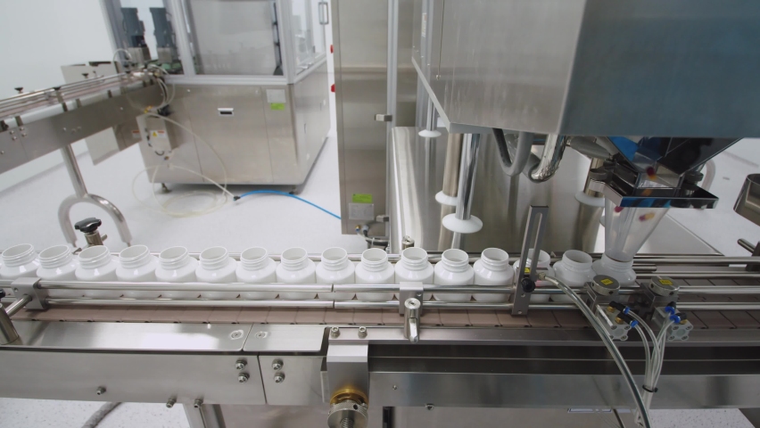 The automated packaging machine is filling the containers with the pills moving on the conveyor line. Royalty-Free Stock Footage #1091825737
