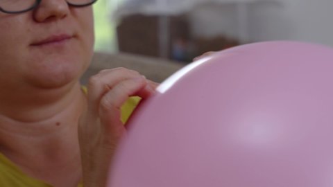 Close-up girl tries to tie a pink balloon but it flies out of her hands and flies away.