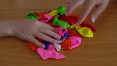 close-up of women's hands quickly pick up colored balloons to inflate them for the holiday