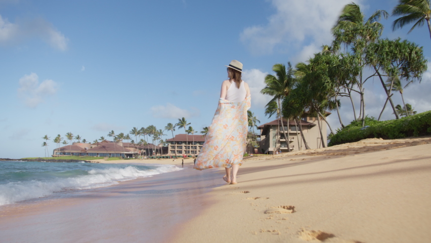 Slow motion enjoying relaxing walk on beach, Hawaii travel vacation lifestyle. RED camera low angle happy woman, embracing and walking on beach on summer morning. Healthy outdoor leisure time by ocean