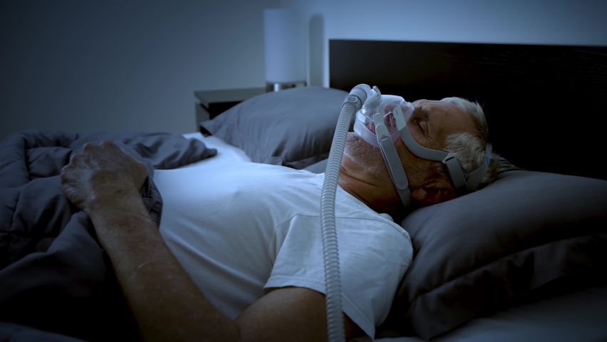 Mature adult sleeping at night while wearing a CPAP mask to treat his Sleep Apnea. | Shutterstock HD Video #1091829255