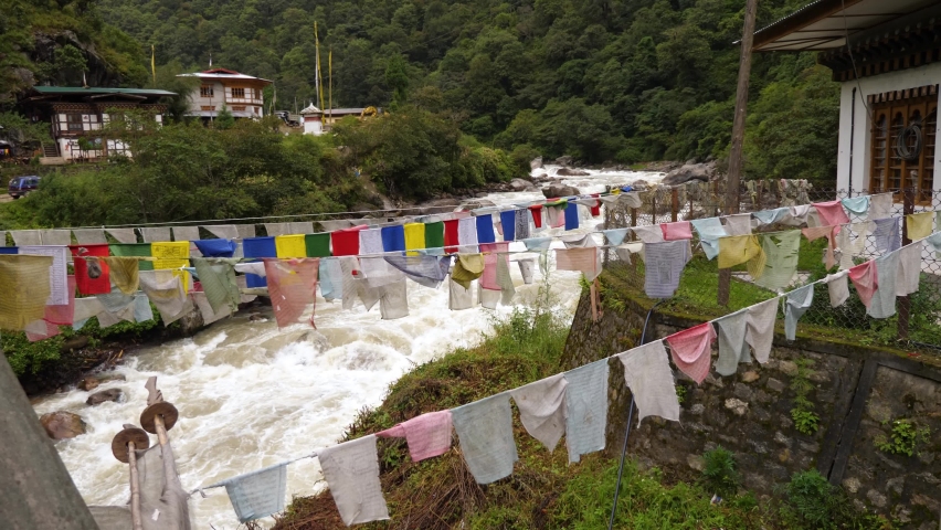 Prayer flags strung across a raging river in the mountains of Bhutan | Shutterstock HD Video #1091829327