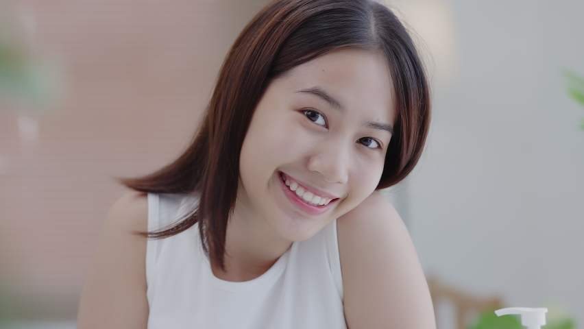 Beauty Face. Closeup headshot portrait of smiling Asian girl with natural makeup and healthy smooth skin looking at camera. Beautiful girl with hydrated facial skin. | Shutterstock HD Video #1091830731
