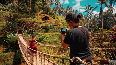 Bali, Ubud - Indonesia - Nov 17 2021: Travel people walking along the picturesque wooden bridge to the famous landmark Bali Tegallalang rice terrace on nature background Bali, Indonesia 4K