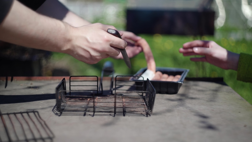 Father and son lay out sausages on a barbecue grill. Close-up shooting