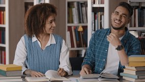 Close-up couple students studying in library preparing for exam working on project read books young girl wakes up sleeping friend funny guy dozing at desk pranks on girlfriend joking laughing smiling - Powered by Shutterstock - Get 15% off with code: PIKWIZARD15