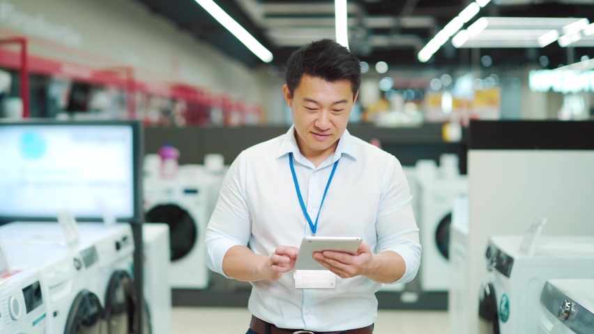 Portrait smiling male asian sales consultant Expert who is standing in a home appliance store looking at camera. Employee Man worker seller smiles. salesman manager vendor with a tablet in his hands | Shutterstock HD Video #1091836323