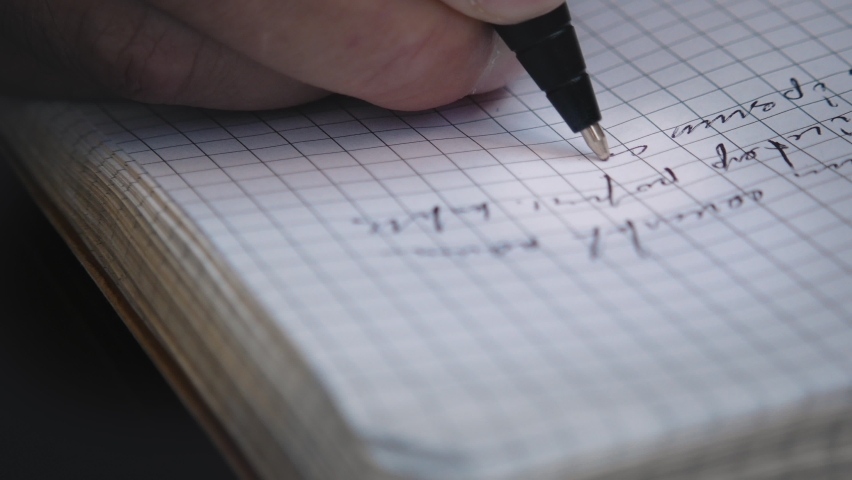Close-up of a pen writing. A person makes notes in a notebook with a ballpoint pen. Fake "Lorem Ipsum" text. Camera is following the pen. Close-up macro. Shallow depth of field.