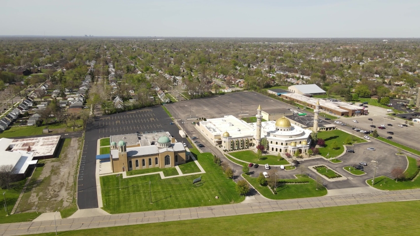 Aerial forwarding descending shot of Islamic Center of America side by side with Christian church, Dearborn Michigan