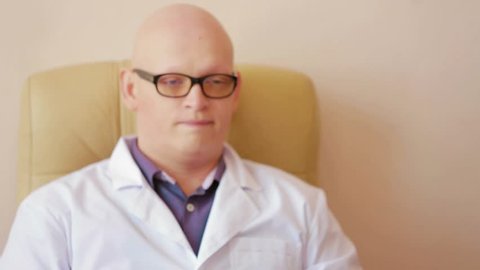 Doctor teacher sits in a chair and looks into the classroom through the glasses. Man unhappy he rubs his bald head saoyu and throws up his hands.