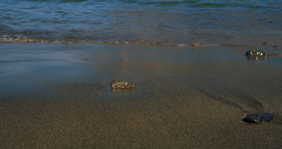 Beautiful landscape, a wave runs on the sandy black bolcanic shore of the ocean beach, close-up. Playa Guios. Tenerife. Canary islands, Spain. High quality 4k footage.