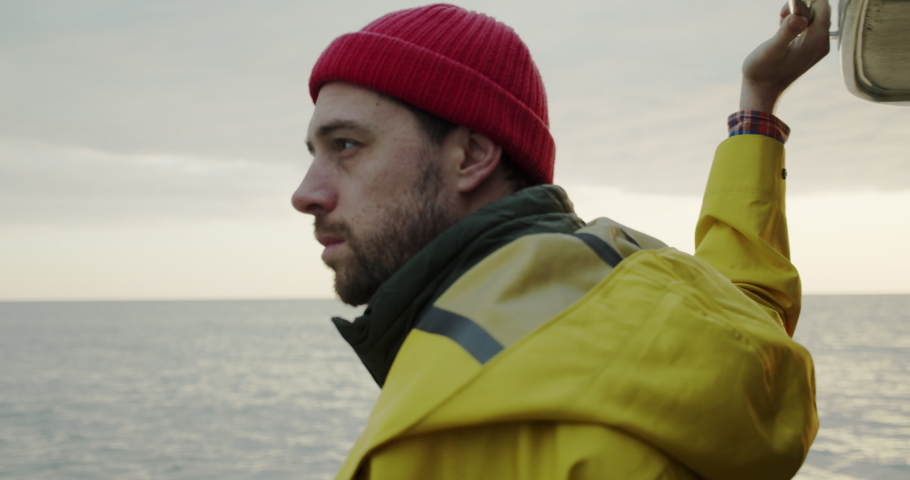Portrait of a smiling sailor sailing on a boat at sunset. portrait of a man in a red hat and yellow raincoat. outdoor activities Royalty-Free Stock Footage #1091849115