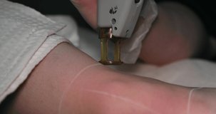 Close-up footage of a female client's leg receiving pulses of laser light destroying a hair follicle. Laser hair removal procedure in a beauty salon. slow motion.