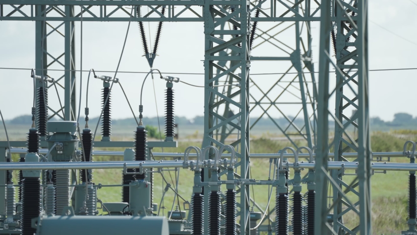 A close-up shot of the electrical power plant. Green fields in the background. Slow-motion, pan left.