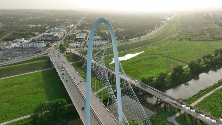 Margaret Hunt Hill Bridge over Trinity River in Dallas Texas. Warm golden hour sunset light. Traffic driving past Texas flag.