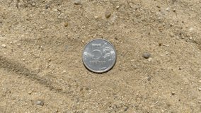Five-ruble coin on sand. Volatility of the Russian ruble. Metal state currency of the Russian Federation. Metal ruble. Exchange rate of the ruble. 4k 3840 × 2160 video.