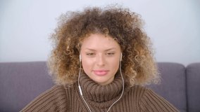 Happy Ukrainian woman in headset talking on video call. Cheerful curly female saying hello to her friends on web camera in 4k  stock video. Royalty free footage clip of cute white person in headphones