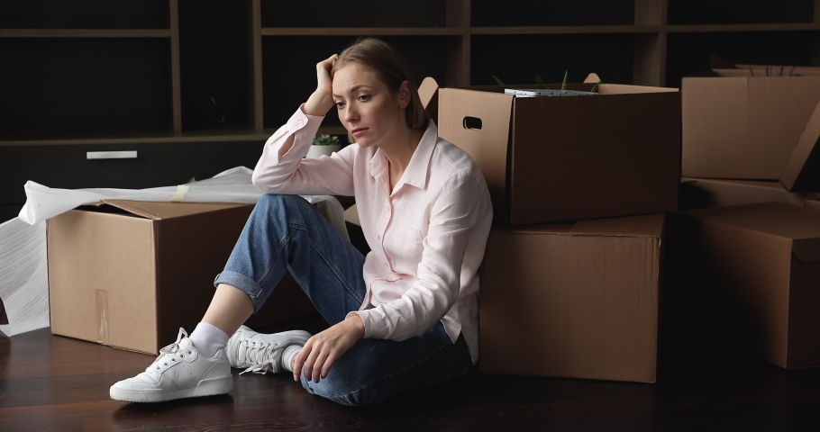 Frustrated young renter girl moving out from apartment, sitting at cardboard boxes at home, thinking over financial problems, job loss, bankruptcy, eviction, housing search Royalty-Free Stock Footage #1091860839
