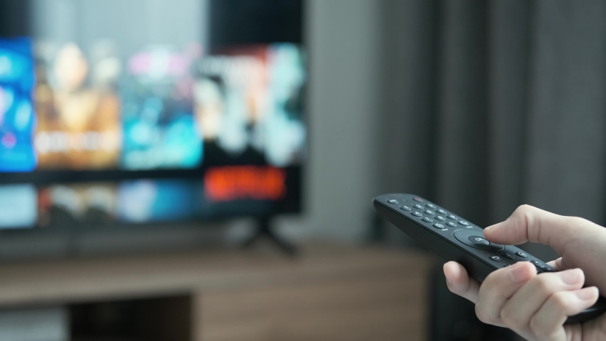 Women hand holding the TV remote control and turn off smart tv. Channel surfing, focused on the hand and remote control. Internet TV at living room on holiday on sofa | Shutterstock HD Video #1091868249