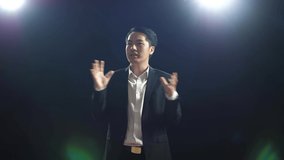 Smiling Asian Speaker Man In Business Suit Holds His Hands Together And Spreads Out His Arms While Speaking In The Black Screen Studio
 - Powered by Shutterstock - Get 15% off with code: PIKWIZARD15