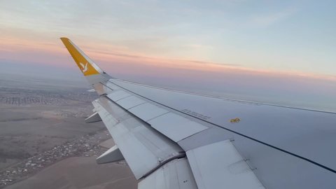 View of the wing of the Turkish airline Pegasus aircraft flying over the outskirts of the city of Almaty at dawn. Almaty, Kazakhstan - 11.10. 2020