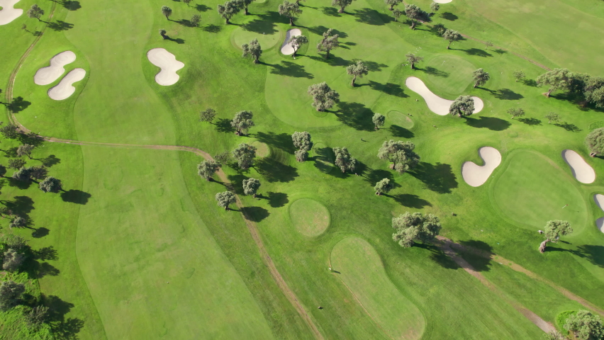 Aerial view of green grass and trees on a golf field. Bird eye view over golf course. Beautiful golf playground field with hills, sand areas and trees. Luxury travel destination Royalty-Free Stock Footage #1091871551