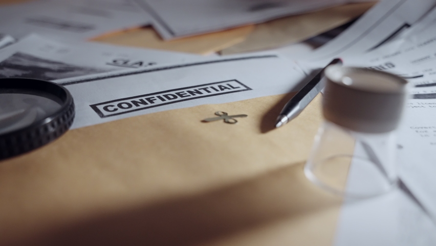 Slow pull out from confidential paper inside brown manila folder or envelope. Top secret information on desk next to other classified documents by military or special investigation agency or spy Royalty-Free Stock Footage #1091875167