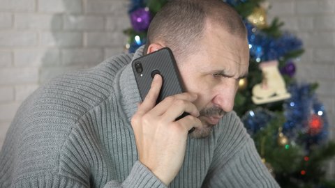 Sad man call at Christmas. A man receive a sad telephone call during Christmas party in the room.