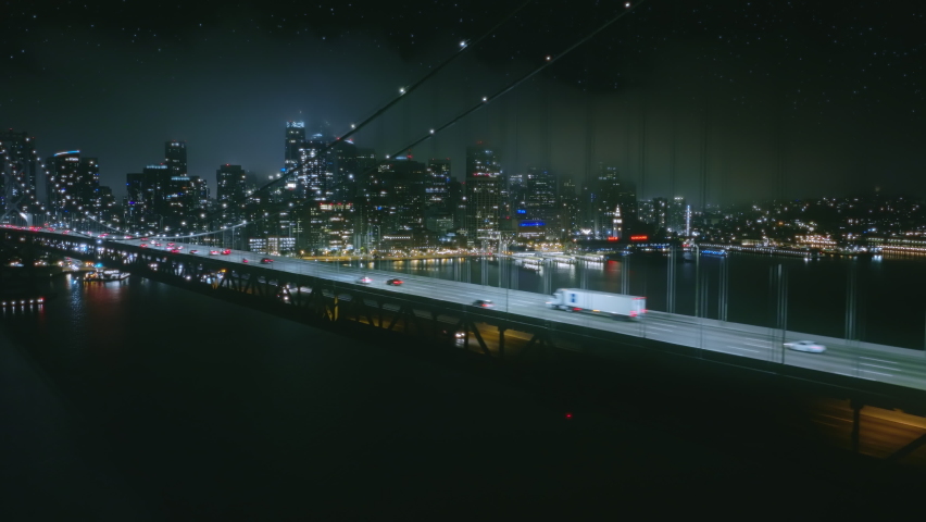 Scenic aerial view of night car traffic on illuminated suspension Bay bridge with San Francisco in foggy cloud on background. 4K urban cityscape, advanced innovation, financial technology energy power