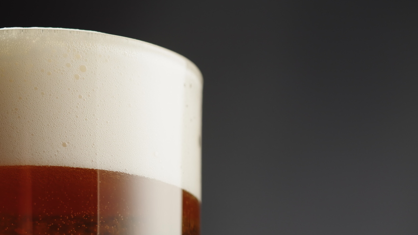 Foamy beer in glass close-up. Alcohol golden beer drink in mug. Fresh pale ale on black background.  Royalty-Free Stock Footage #1091881729
