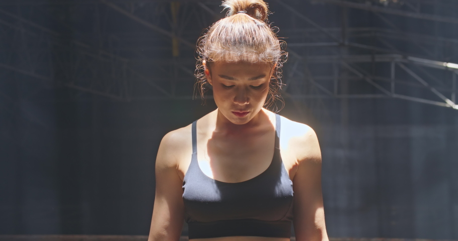 Close up of pretty sportswoman expressing her emotions after exercising. Portrait of young tired and sweaty asian woman boxer looking at camera and screaming loudly with anger on face at dark gym hall Royalty-Free Stock Footage #1091887249