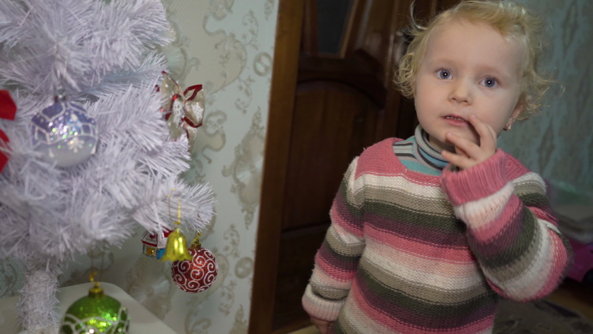home video of a child next to a Christmas tree,memories of childhood at Christmas, a happy little girl looks at the Christmas tree