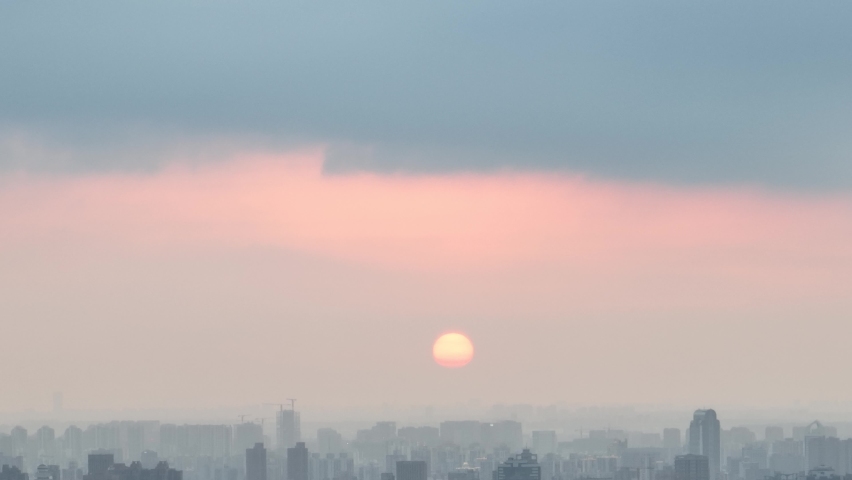 Drone aerial view of City in the dusk and the orange sunset glow. Flying over the city with rows of buildings, beautiful sunset Shanghai China. Business, travel and life style concept b-roll footage.