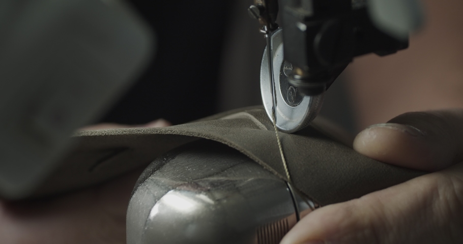 Tailor works on sewing machine in private leather craftshop, making shoes in process. male seamstress sewing leather shoes in leather workshop in 4k Royalty-Free Stock Footage #1091895617