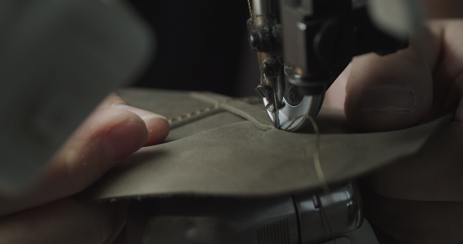 Tailor works on sewing machine in private leather craftshop, making shoes in process. male seamstress sewing leather shoes in leather workshop in 4k | Shutterstock HD Video #1091895629