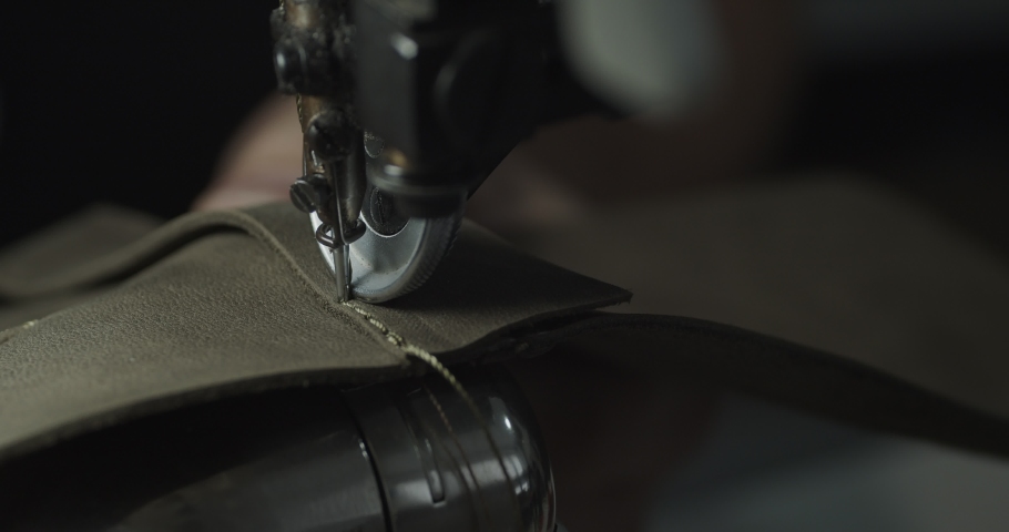 Tailor works on sewing machine in private leather craftshop, making shoes in process. male seamstress sewing leather shoes in leather workshop in 4k Royalty-Free Stock Footage #1091895651