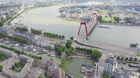 Inscription on video. Rotterdam, Netherlands. Williamsburg Suspension Bridge over the Nieuwe Maas River. Shimmers in colors purple, Aerial View