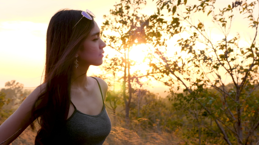 Happy love couple take photo and selfie during camping and relax in forest hiking trip, beautiful Asian woman and caucasian man happiness spend time tpgether, sunset liesure romantic moment
