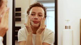 Young brunette woman washing cleaning face with organic foamy soap cleanser, looking in the mirror in bathroom. Making massage movements. Morning beauty procedure routine, healthy skin care concept - Powered by Shutterstock - Get 15% off with code: PIKWIZARD15