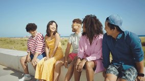 Group of friends having fun on the beach. Multiethnic Teenagers having a good time during the summer celebrating together next to the ocean.
