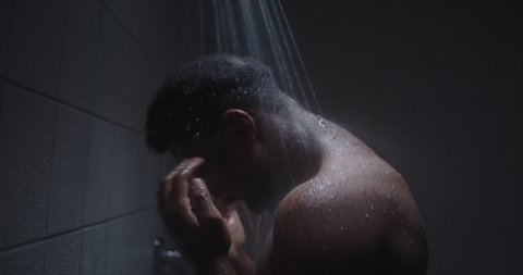Young black male taking hot steaming shower in shower room.