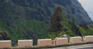 Attractive young woman in white dress walks in the mountains village Masca, green hills and rocks landscape, slow motion. Tenerife.
