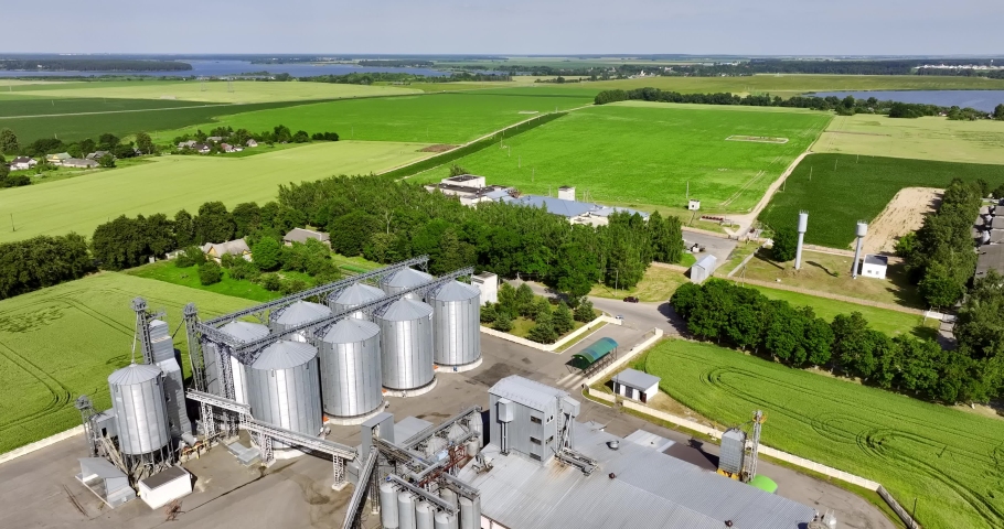 aerial view over agro silos granary elevator on agro-processing manufacturing plant for processing drying cleaning and storage of agricultural products, flour, cereals and grain.  Royalty-Free Stock Footage #1091913583