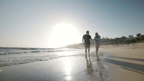Happy friends enjoying natural landscape by the endless ocean and sunset skyline above. Idyllic perfection of natural lighting and calm sea waves. High quality 4k footage