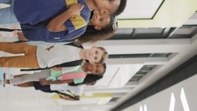 Video of happy diverse pupils standing in row and smiling before entering classroom. primary school education and learning concept.
