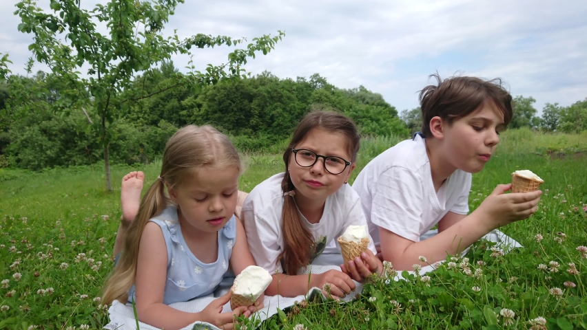 Children eat ice cream in the park and spend time together, summer holidays
